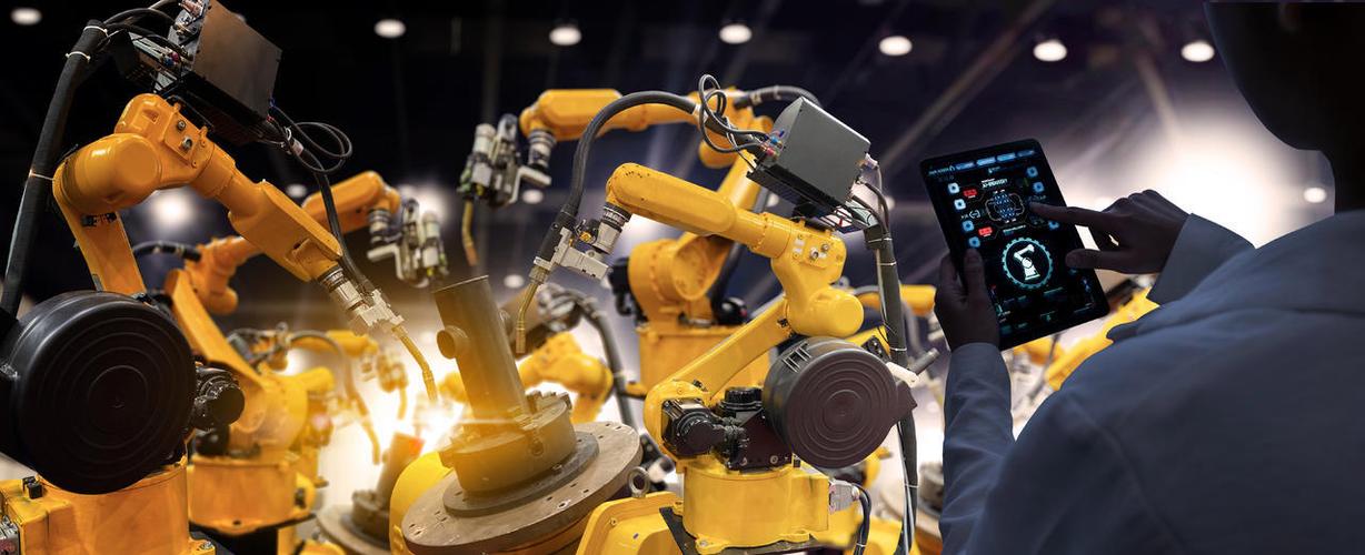 工业工程师在智能化工厂的自动化机械臂机器上进行实时监测系统软件的
